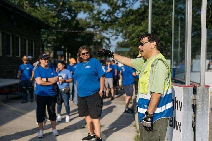 A person in a vest pointing at a group of people AI-generated content may be incorrect.