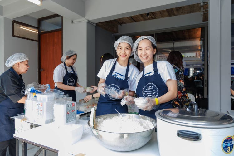 Two ladies cooking food it a kitchen with aprons on