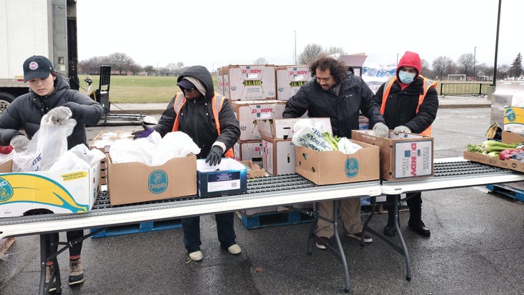Assembly line of volunteers prepping to hand out food to cars