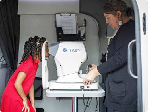 A person and child looking at an eye test machine AI-generated content may be incorrect.